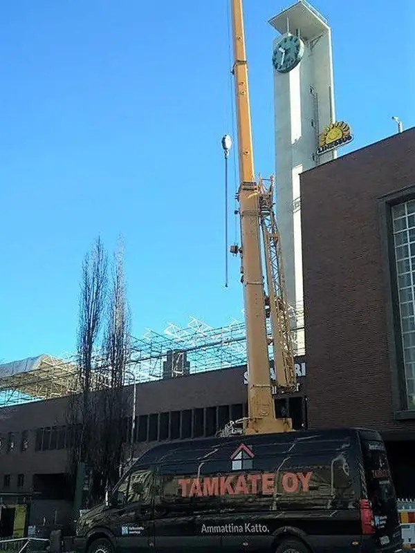 Nosturi nostaa materiaalia kerrostalon katolle, Tamkaten auto alla
