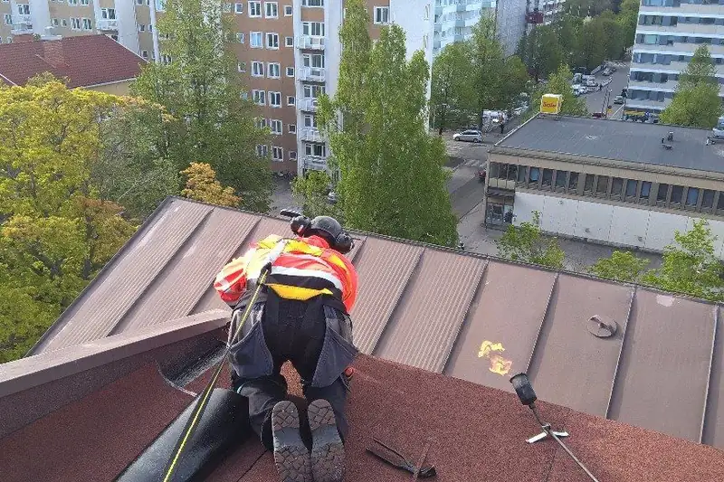 Asentaja valjaissa peltikatolla kaupungin yllä